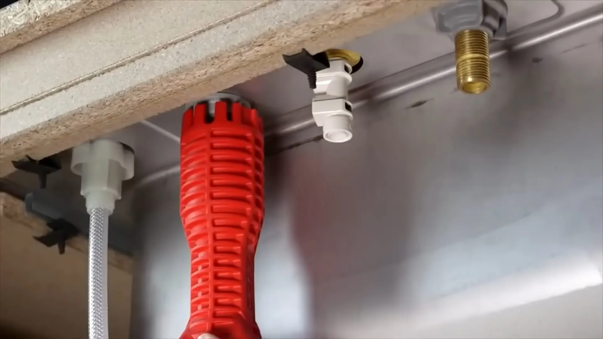 Basin wrench gripping a fitting under a sink