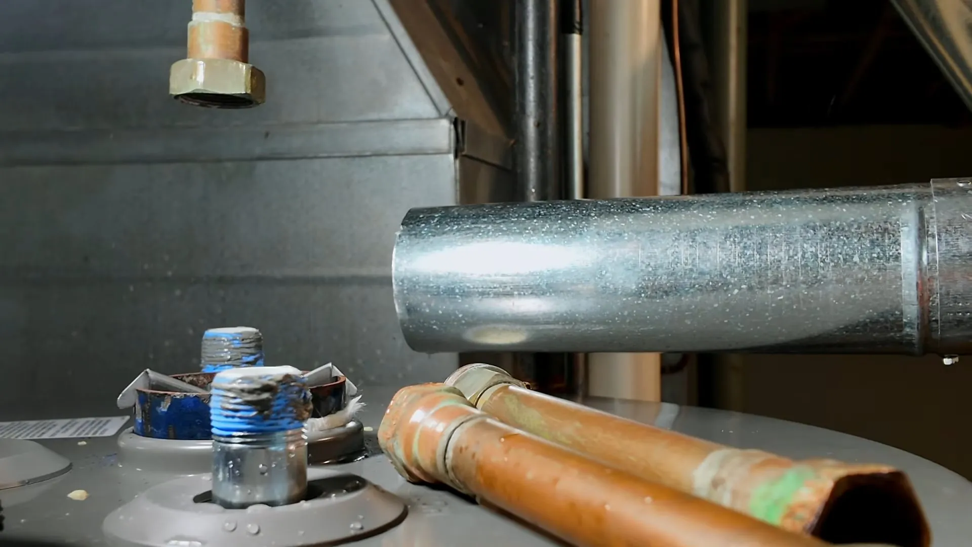 Copper pipe, a capped fitting and a metal vent pipe on top of a water heater
