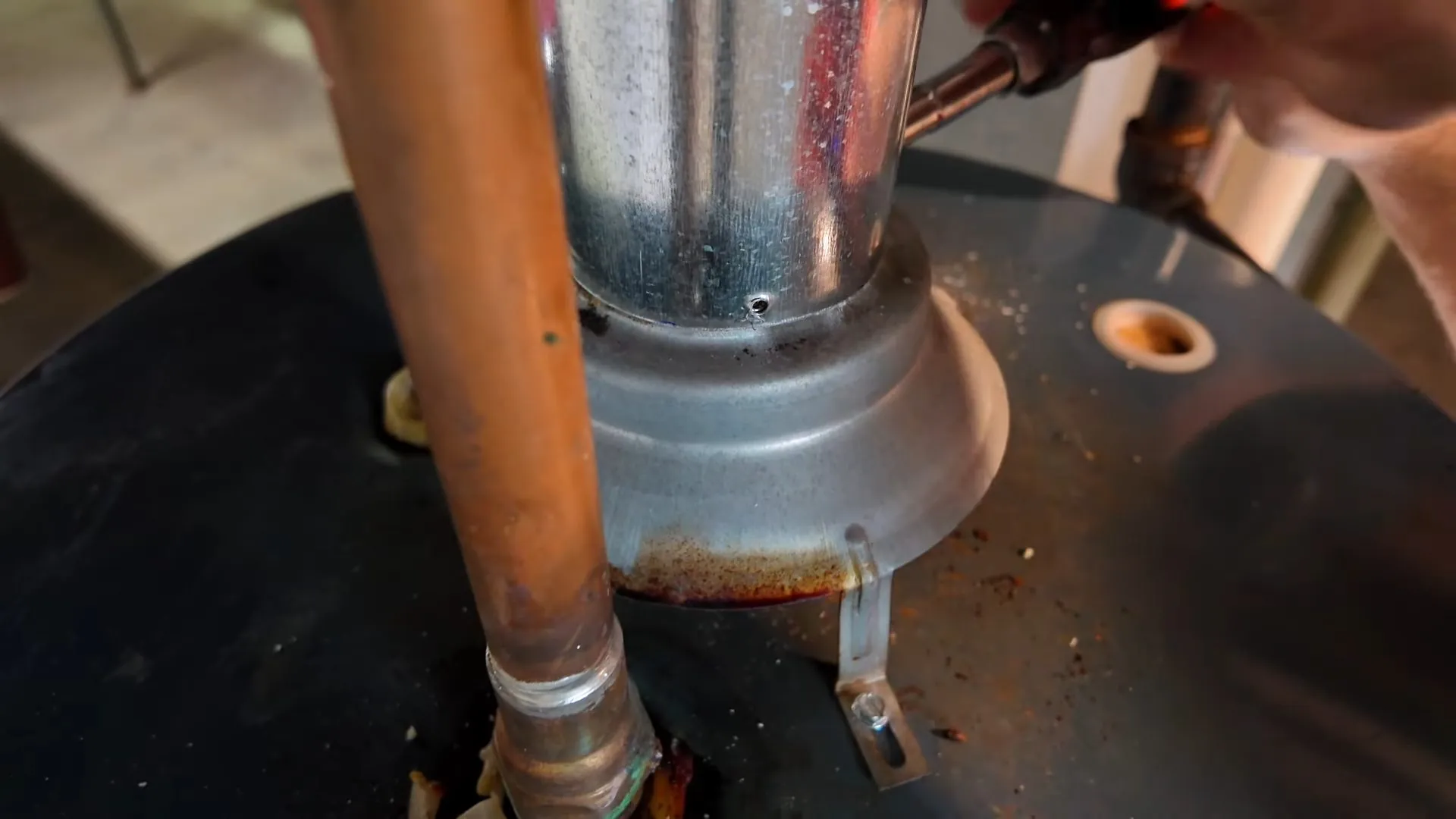 Flue collar and copper supply pipes on top of a tank heater during installation