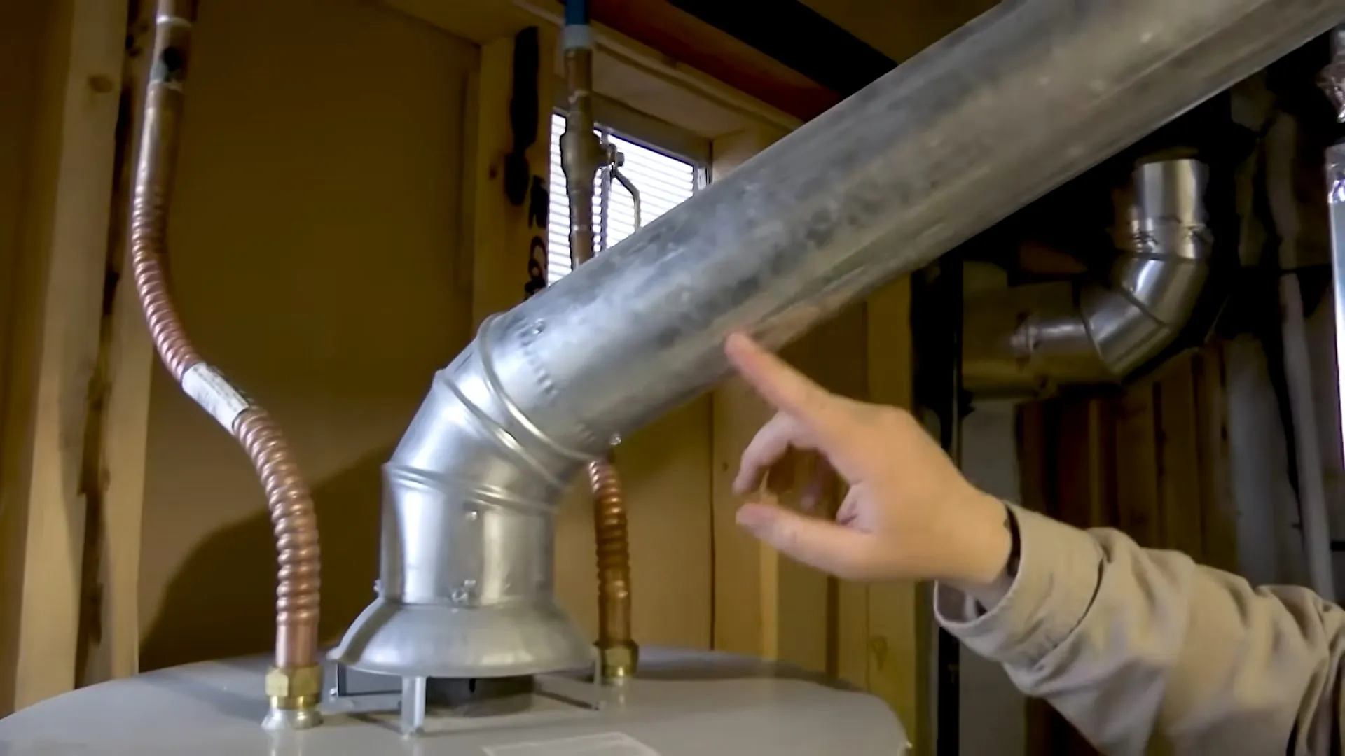 Hand at the flue elbow on top of a tank water heater