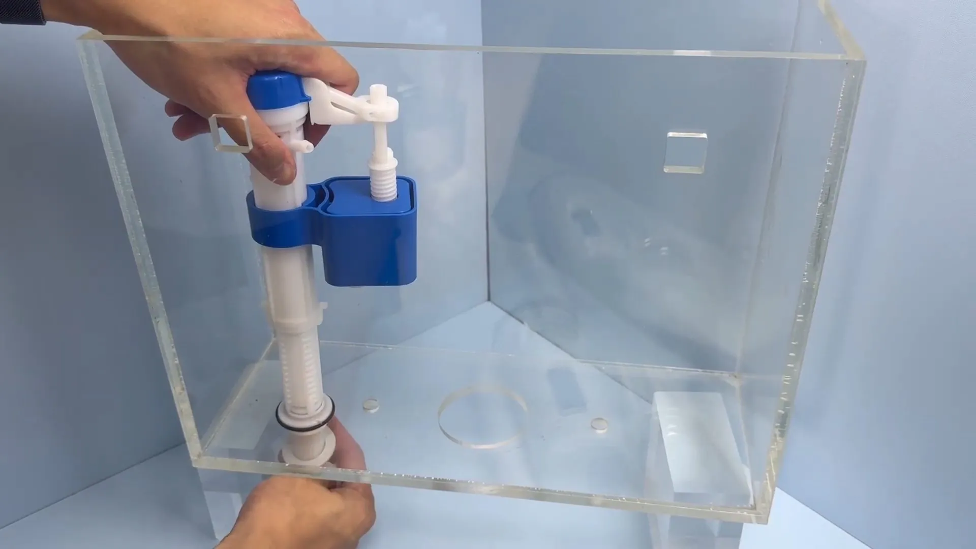 Hands installing a fill valve in a clear toilet tank