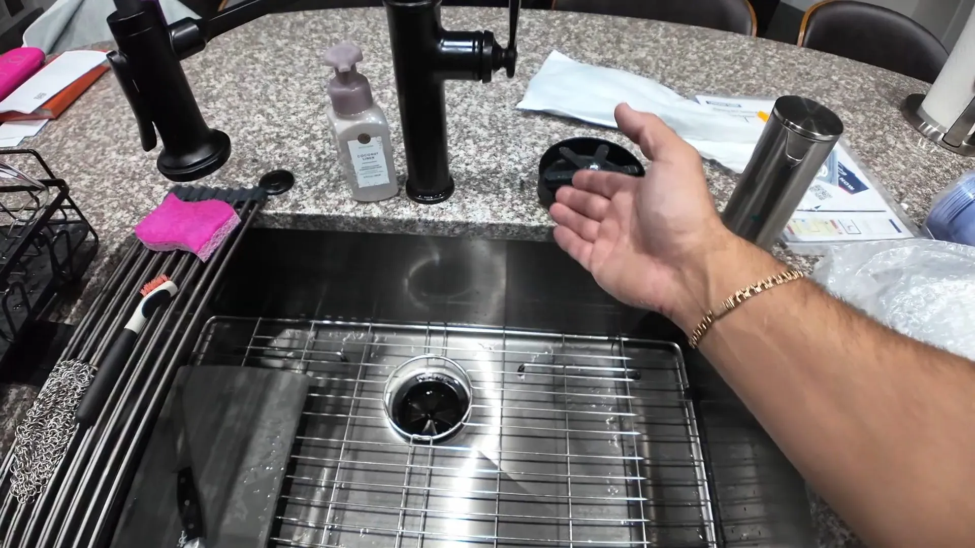Kitchen sink drain and strainer with a hand reaching in beside it
