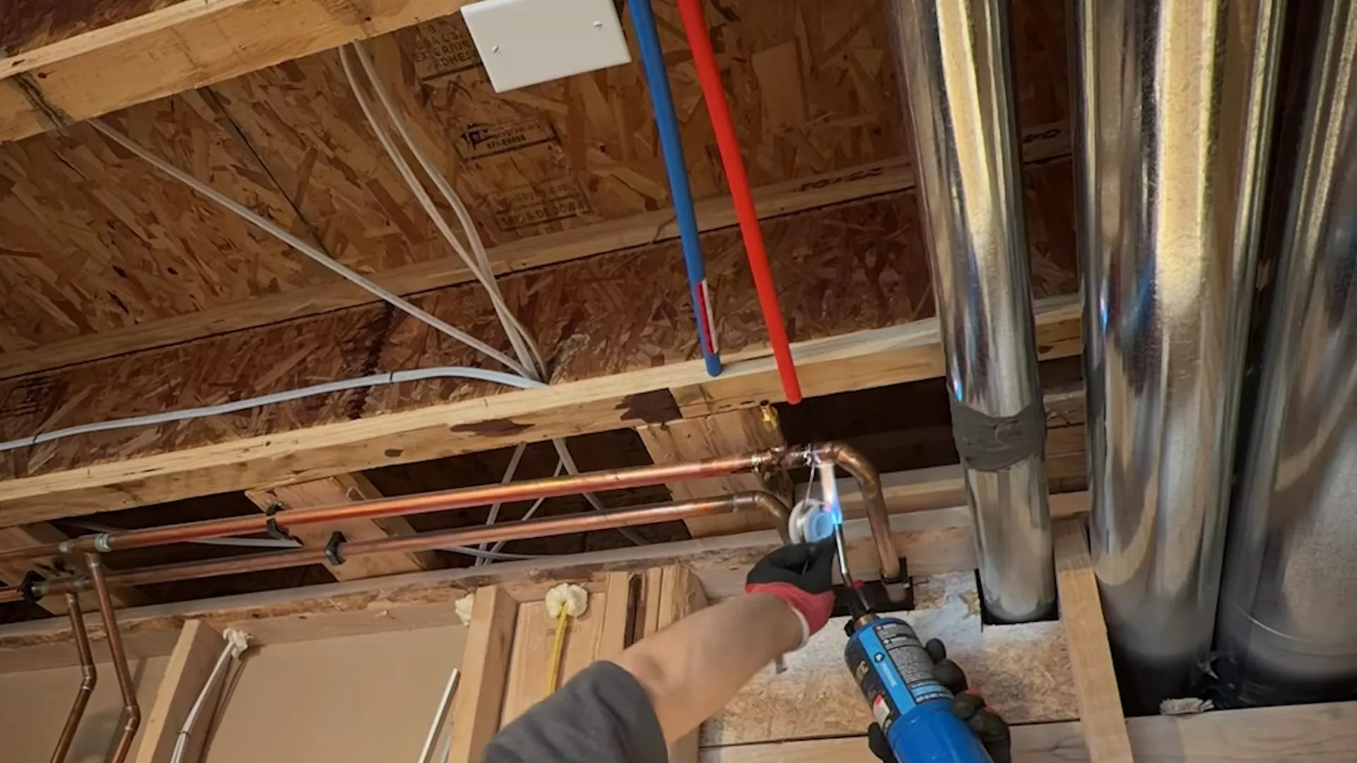 Open wall framing with new copper and red and blue PEX lines being installed