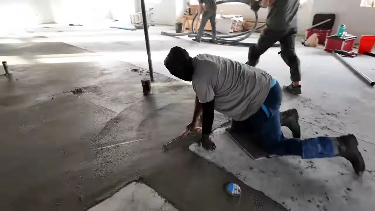 Plumbers at work on a bare concrete floor in an unfinished commercial space