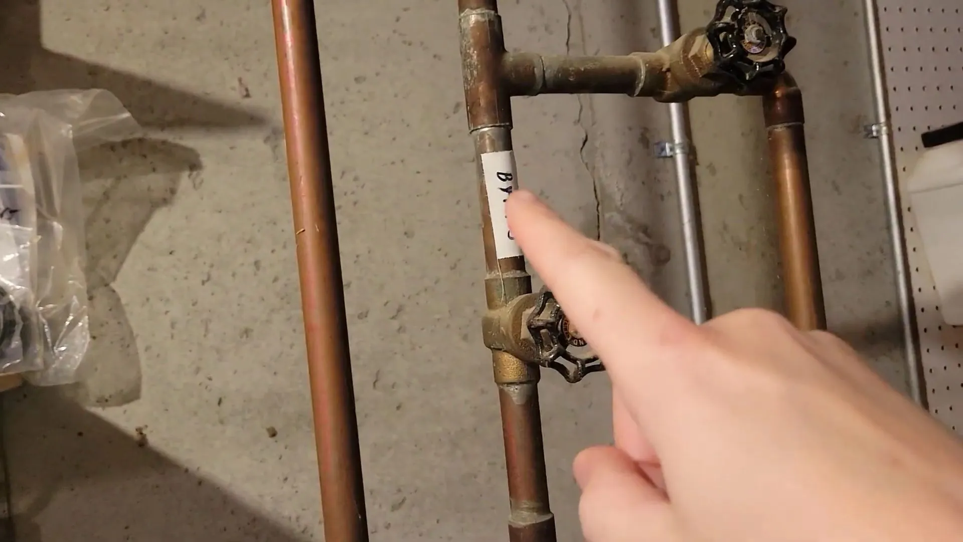 Finger pointing at two brass shutoff valves on copper supply lines