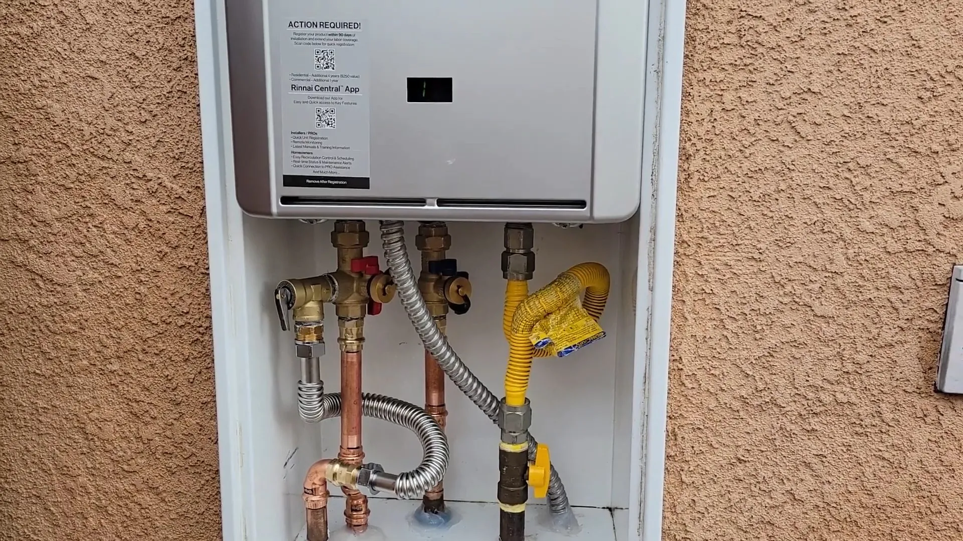 Wall-mounted tankless water heater with gas and water lines running beneath it