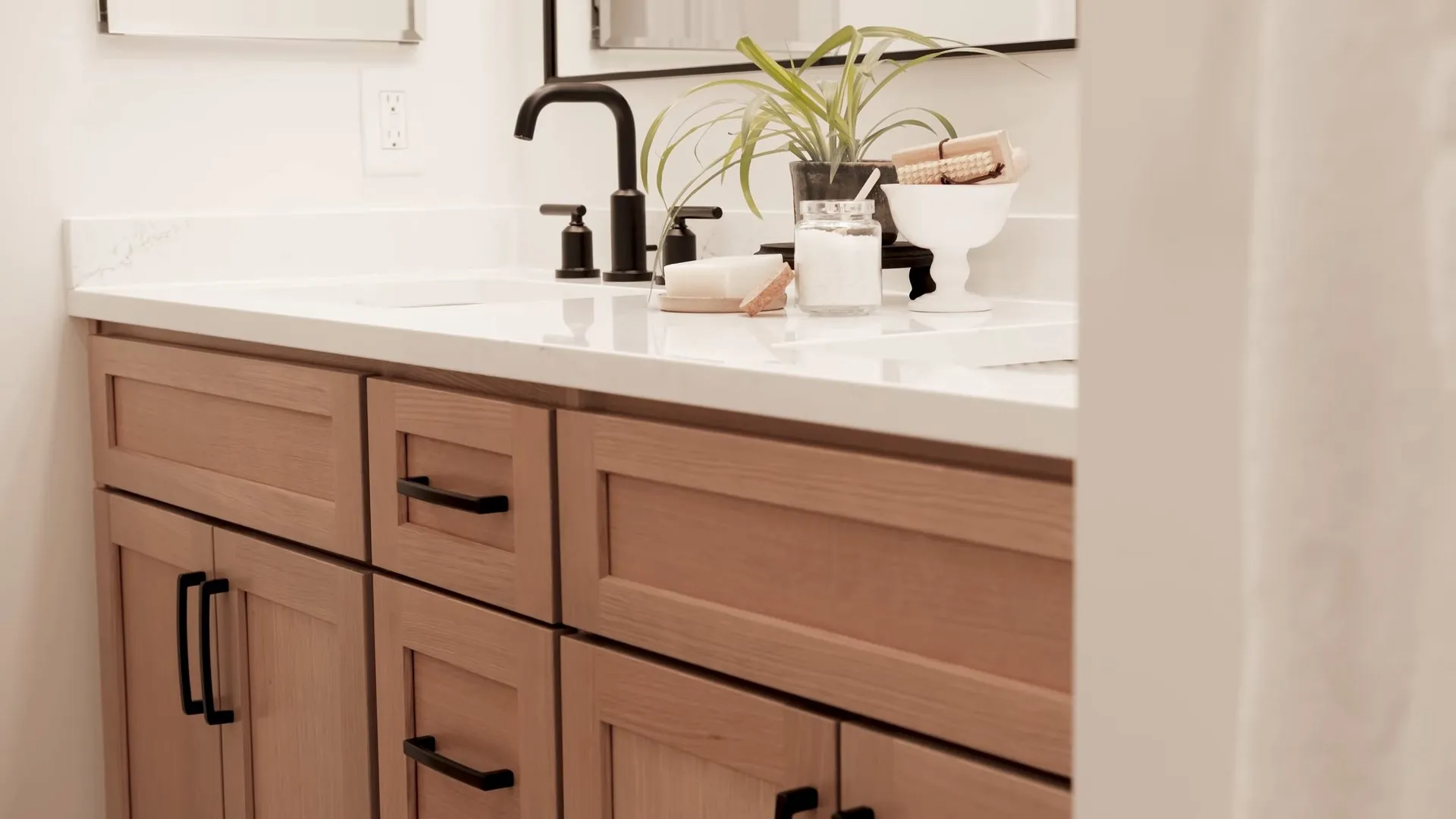 Wood-faced vanity with a white top, a black faucet and two cabinet doors below